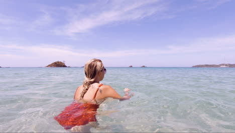 joven y hermosa mujer sentada en los océanos cristalinos de la playa de nacpan en el nido filipinas mientras la cámara gira, vacaciones perfectas y destino de ensueño
