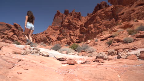 mujer joven caminando en el paisaje desértico seco rojo del parque estatal del valle del fuego, nevada usa, revelando la inclinación de cámara lenta hacia arriba
