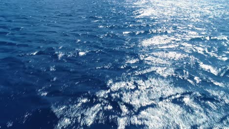 light rays reflect off of deep blue tropical ocean waters as ripples spread