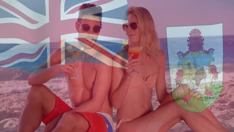 flags of bermuda and united kingdom animation over couple enjoying drinks on beach