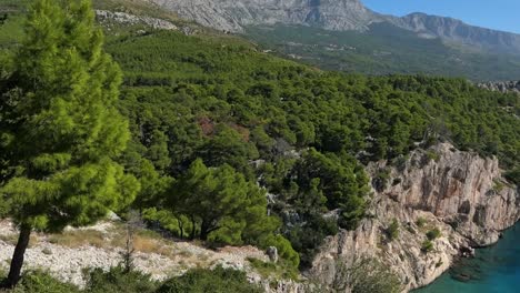 Stunning-hidden-paradise-beach-by-lush-green-mountains,-cinematic,-Mediterranean