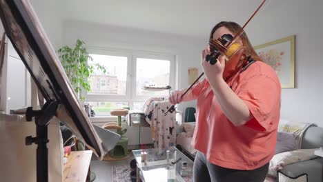 En-La-Comodidad-De-Su-Hogar,-Una-Joven-Practicando-Su-Hobby-De-Tocar-El-Violín