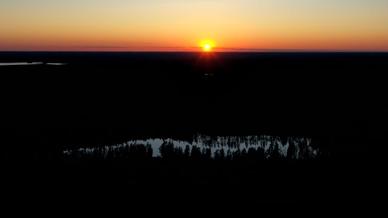 Aerial Hyperlapse, drone shot over forest and a pond, at the countryside, towards the sunset, on sunny summer evening, in Scandinavia - motion time lapse, drone shot