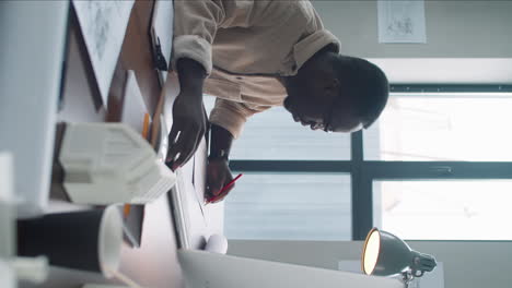 african american male architect using computer and taking notes