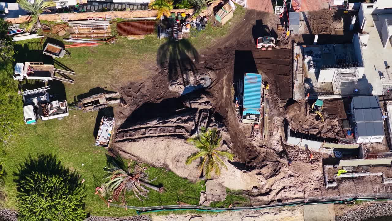 Drone footage captures construction site with workers and machinery in Gold Coast, Australia. Bright daylight highlights progress and activity