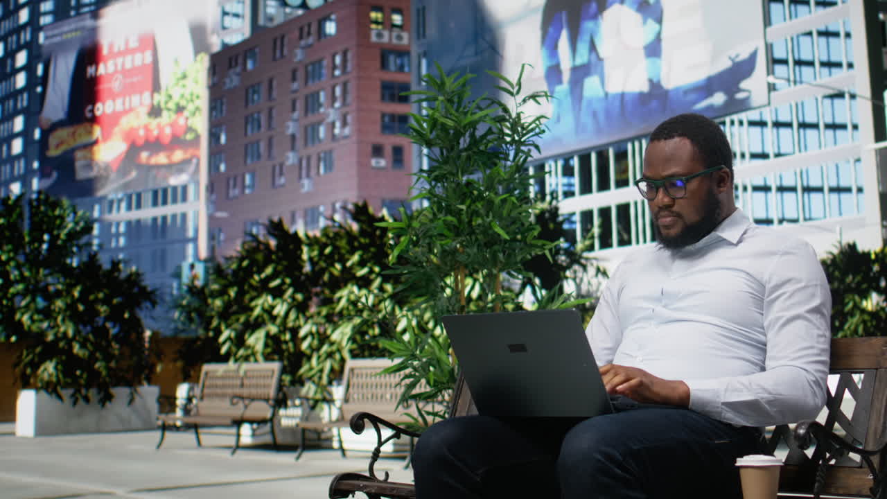 Homem negro sentado em um banco navegando em uma página da internet no laptop