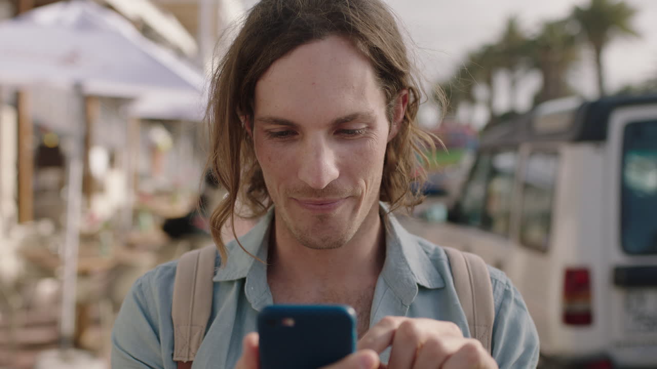 ritratto di un giovane che usa uno smartphone, invia messaggi, naviga sui social media in una giornata di sole