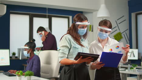 Coworkers-with-face-visor-in-new-normal-office-comparing-graphs