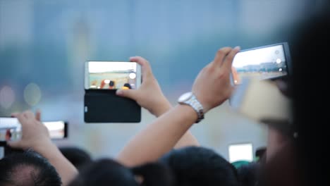 people taking pictures with smartphones at an outdoor event