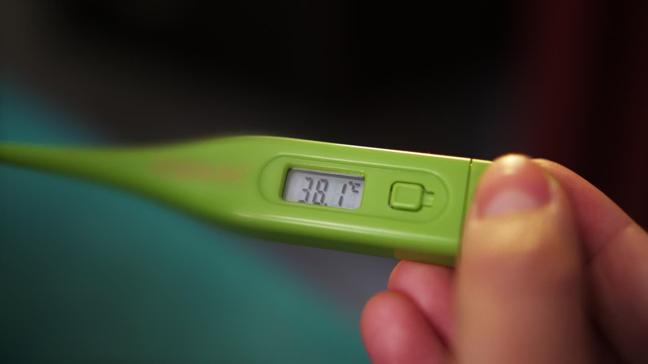 Close-up of Hand Holding Digital Thermometer Showing High Temperature