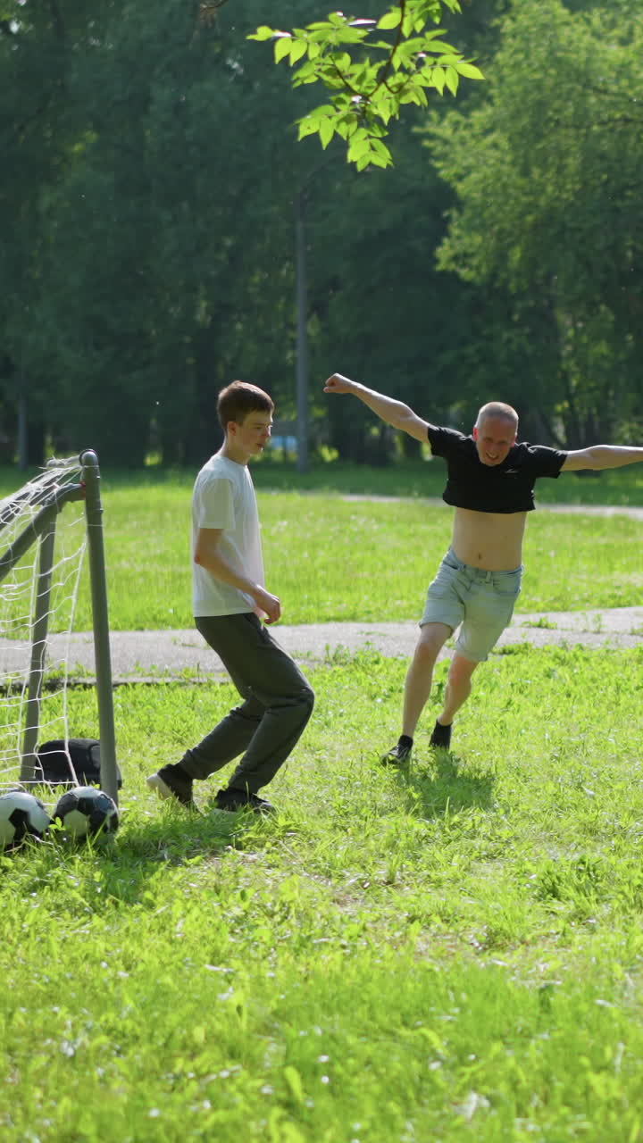 una familia juega un juego de fútbol al aire libre, donde el hijo pequeño patea la pelota mientras celebran y el portero se sienta en el suelo, cubriendo su cara de vergüenza después de perder el rescate