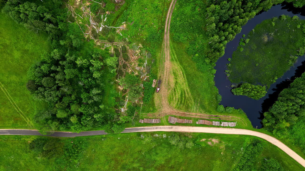 Top down view of vehicle, machine picking up cutted wood on a green grassland path, industrial, zoom in