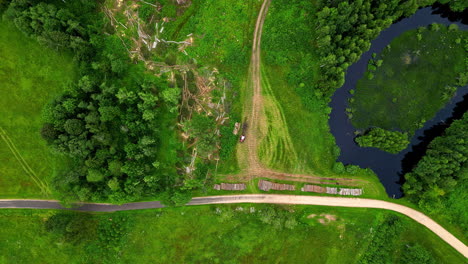 top down view of vehicle, machine picking up cutted wood on a green grassland path, industrial, zoom in