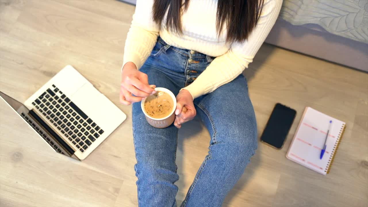 Woman sitting on the floor with laptop and coffee