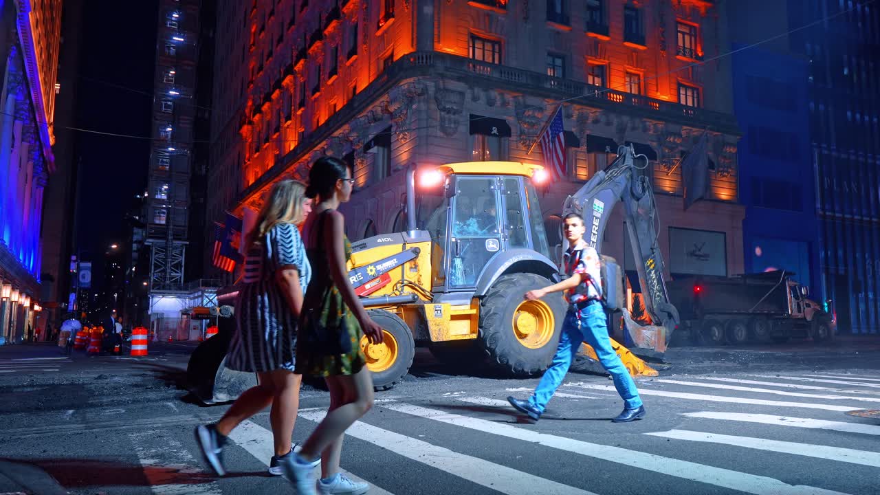 New York, USA, 5. lokakuuta 2025: Keltainen kaivurikuormaaja pysäköitynä suojatielle yörakennustöiden aikana. Sivukuva John Deere -kaivurikuormaajasta Manhattanin kadulla iltaisten infrastruktuurikorjausten aikana