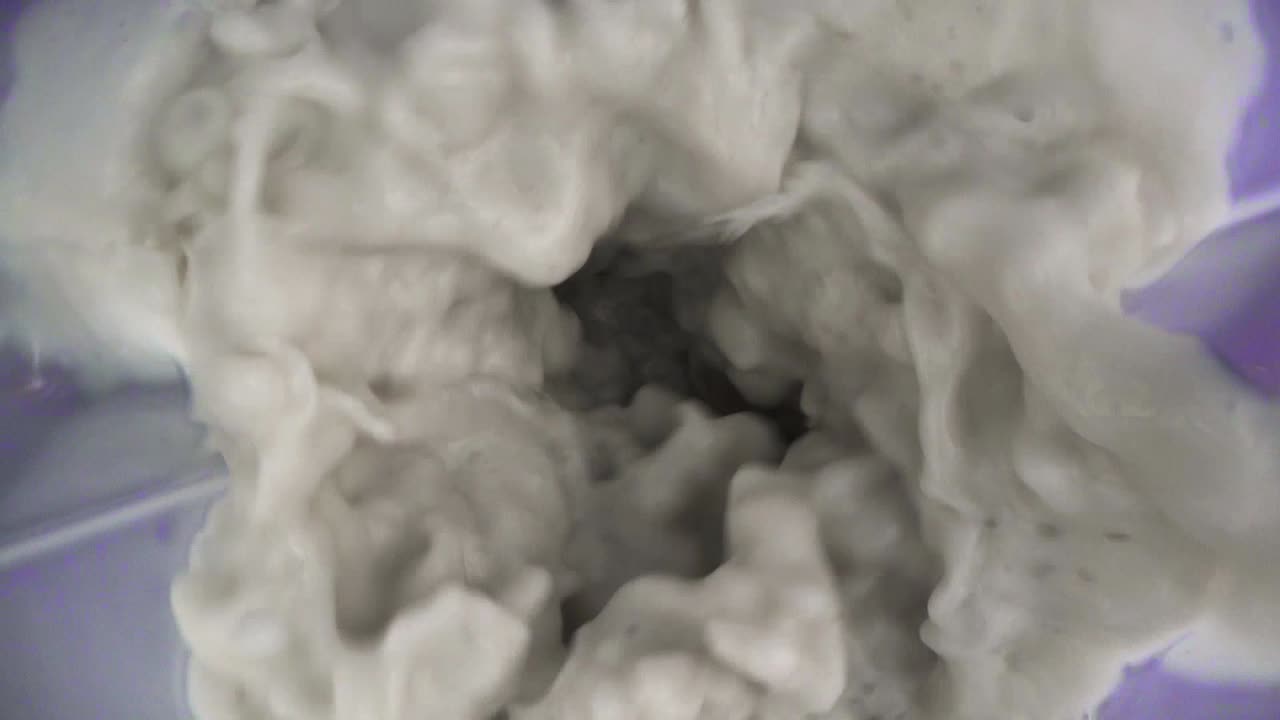 leche volando en una licuadora a cámara lenta de cerca con fondo púrpura vista de arriba hacia abajo