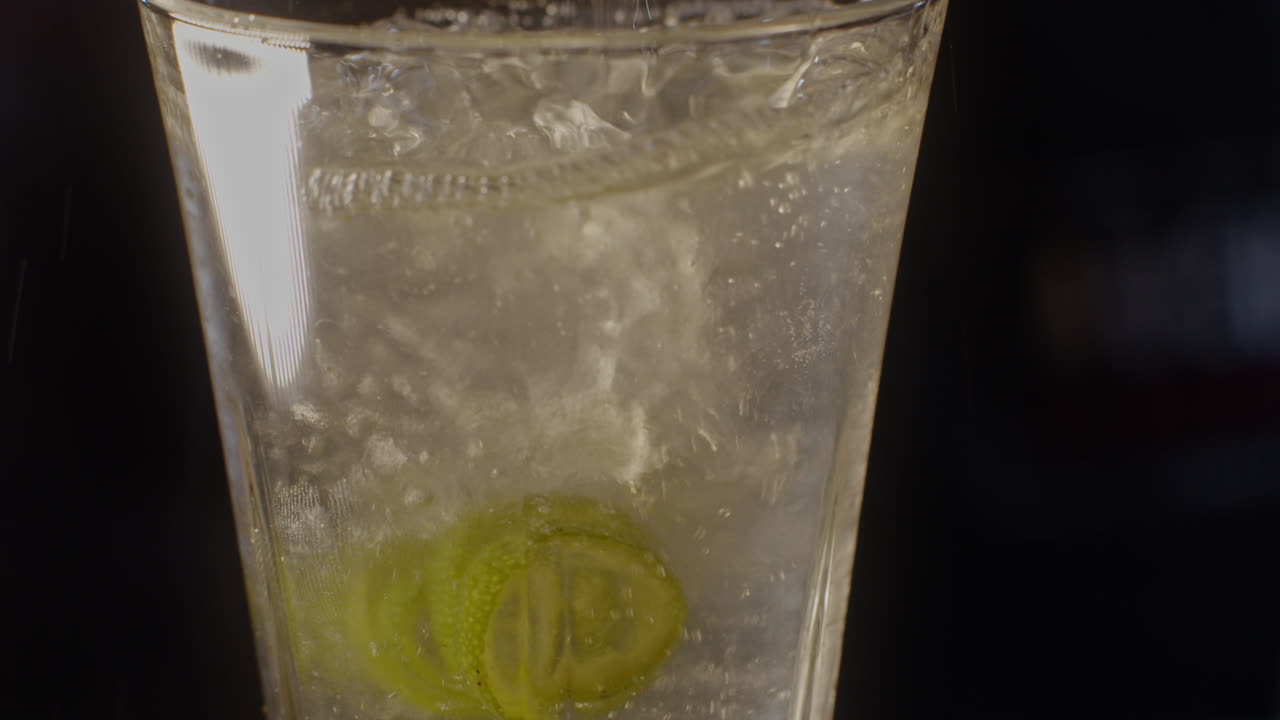 Pouring a refreshing drink with lime and ice