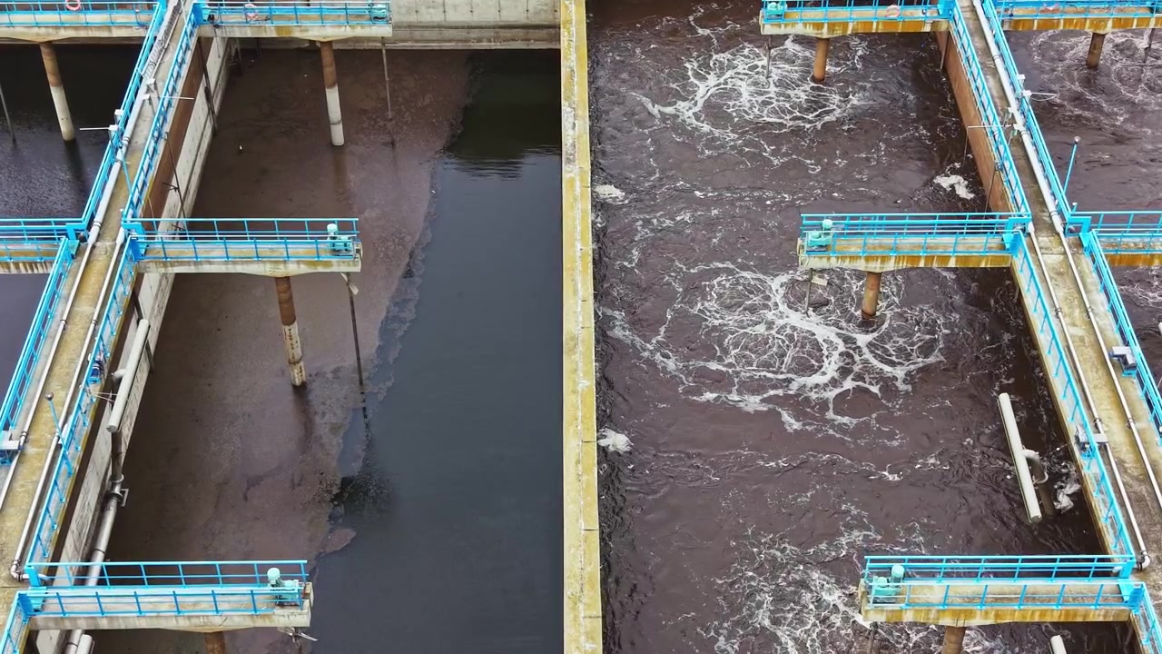 Wastewater treatment facility in operation with several tanks and water flow visible during daytime