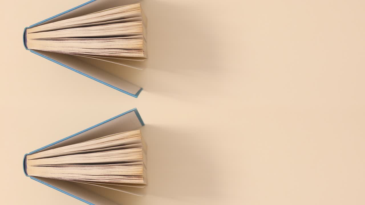 dos libros antiguos de tapa dura azules que pasan sobre un fondo beige.