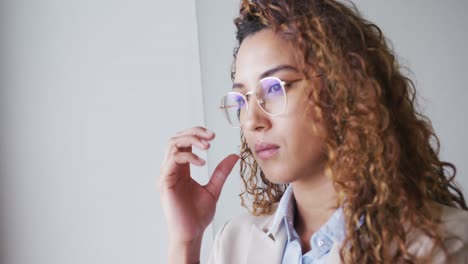 Portrait-of-biracial-businesswoman-taking-glasses-in-modern-office