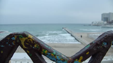 from-behind-an-old-stained-with-color-fence,-the-black-sea-is-revealed-on-this-gloomy-day