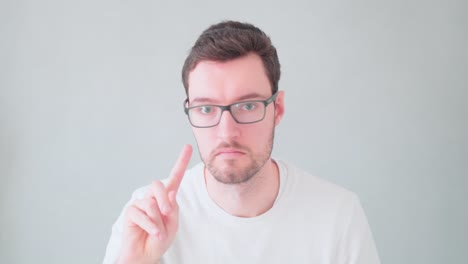 young man wiggles finger, refusal no, must not, dissatisfied, expression emotion portrait hipster man beard glasses