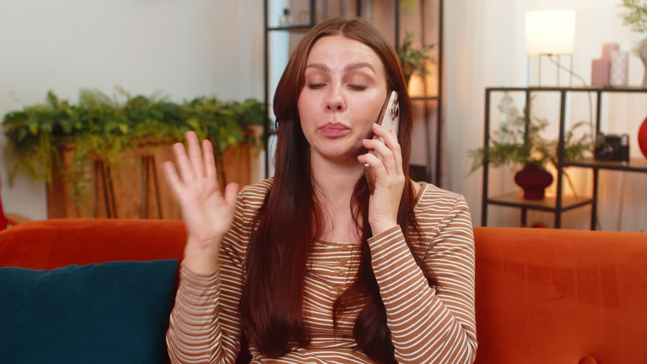 Young woman argues on smartphone frowns sharp hand moves raises voice and speaks fast in tense call