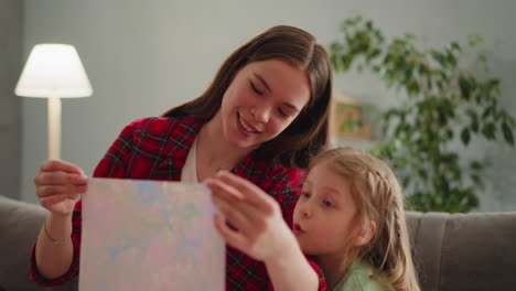 young nanny with funny little girl looks at ebru picture