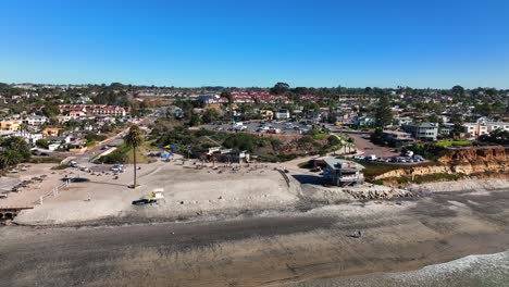 drone shot taken over the town of encinitas, california, usa from the moonlight beach with the view of residential houses, parking lot, roads and first aid center on a sunny day