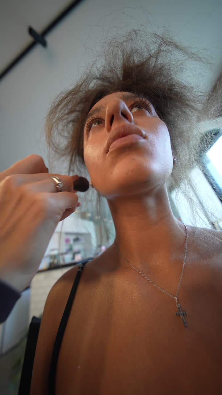 Primo piano di una donna che si fa applicare il trucco con un pennello.