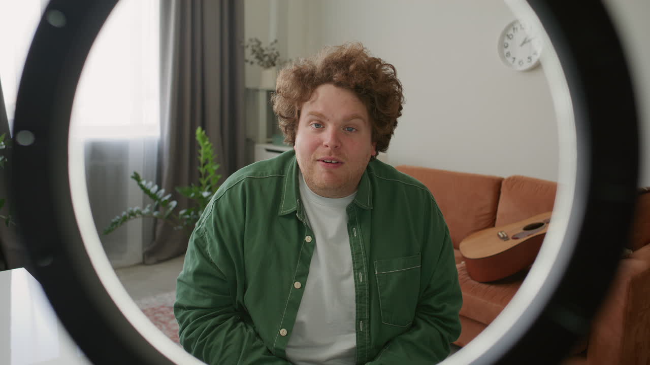 Young Man Waving andвЂ‹ Talking on Camera as Filming Vlog at Home
