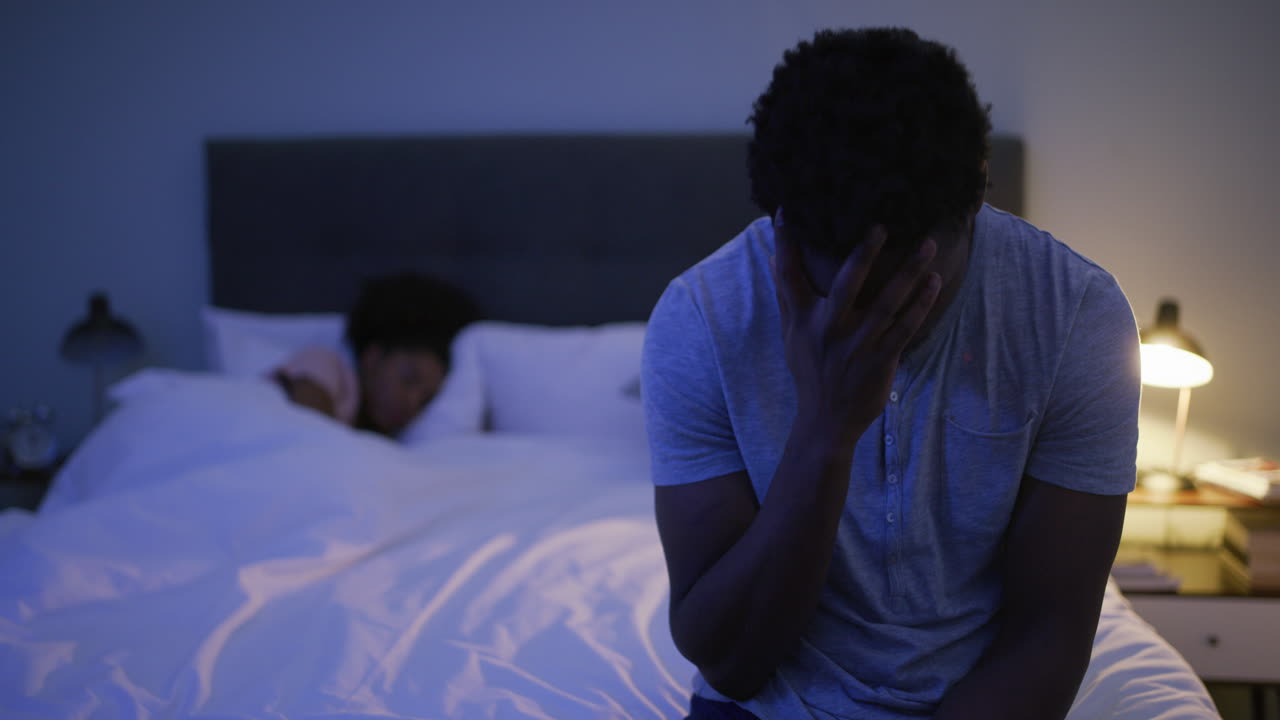 un joven que se ve molesto mientras su esposa duerme
