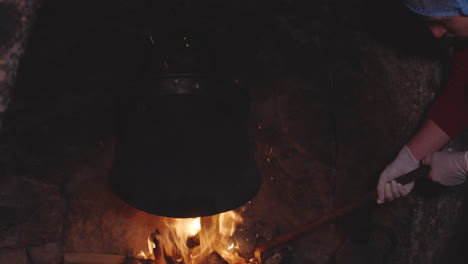 mujer con varilla de acero larga fijando maderas en horno antiguo