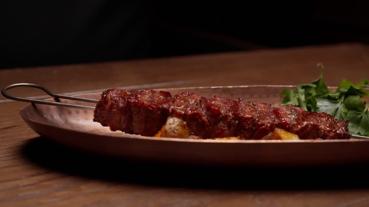 Mano che serve un delizioso kebab di carne con contorni su un tavolo di legno