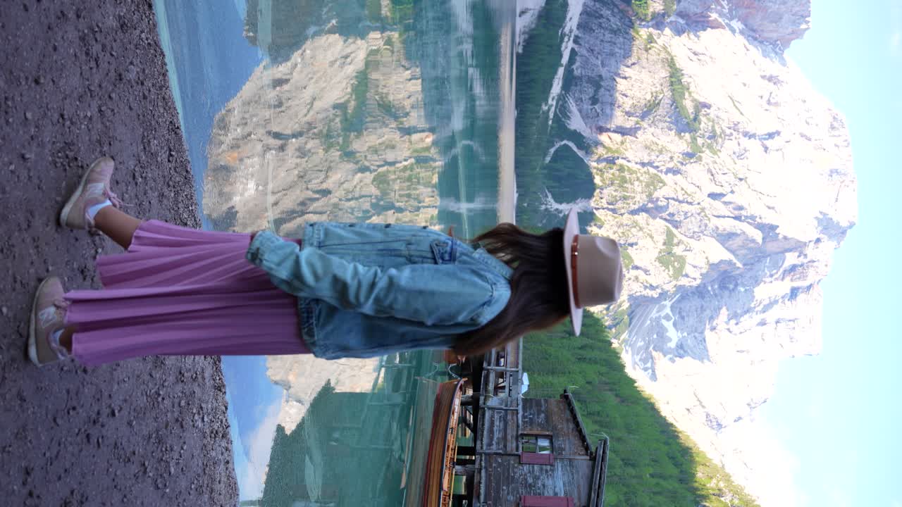 mujer paseando por el lago di braies con croda del becco en el fondo, italia