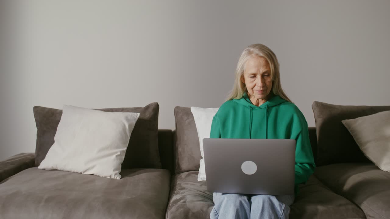 mujer mayor trabajando en una computadora portátil en casa