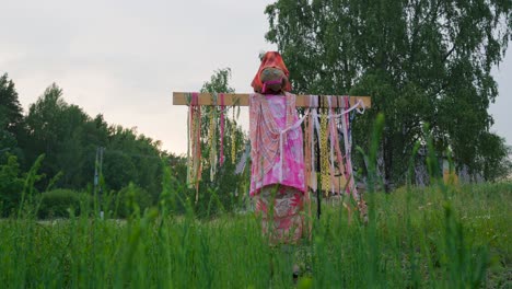 colorful humanlike bird scarer in a grassy field on a cloudy summer evening