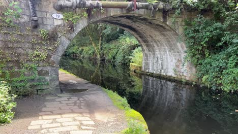 old stone bridge over a english canal showing towpath and old pipework