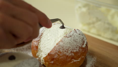 baker is getting some pastry ready placing a chocolate chip in the center of a pastry