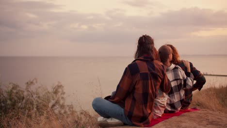 shooting from behind: two couples rest on the seashore and look to the right into the distance. rest in the country house by the sea