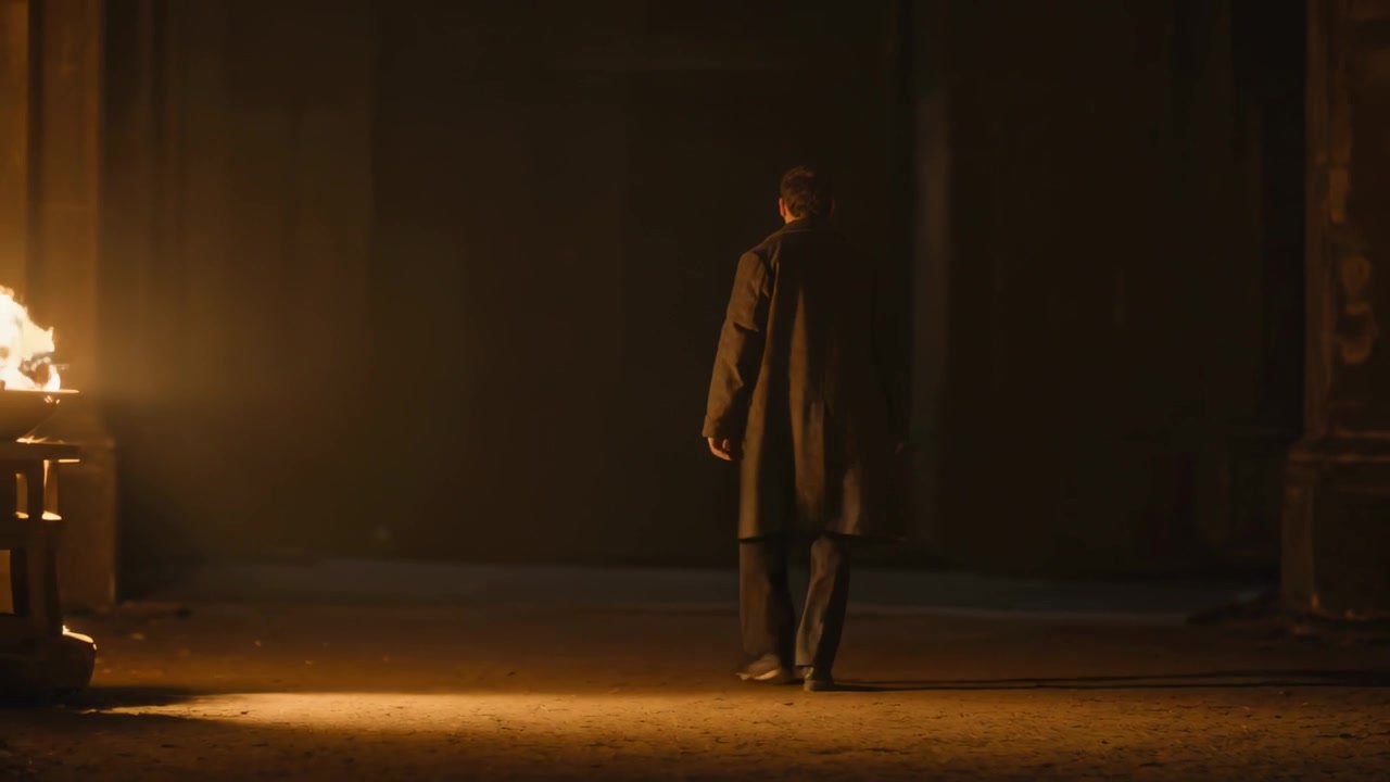 Walking man in long dark overcoat holding rod, brazier lighting hall while heading toward far wall