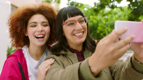 playful female friends taking selfies with a phone