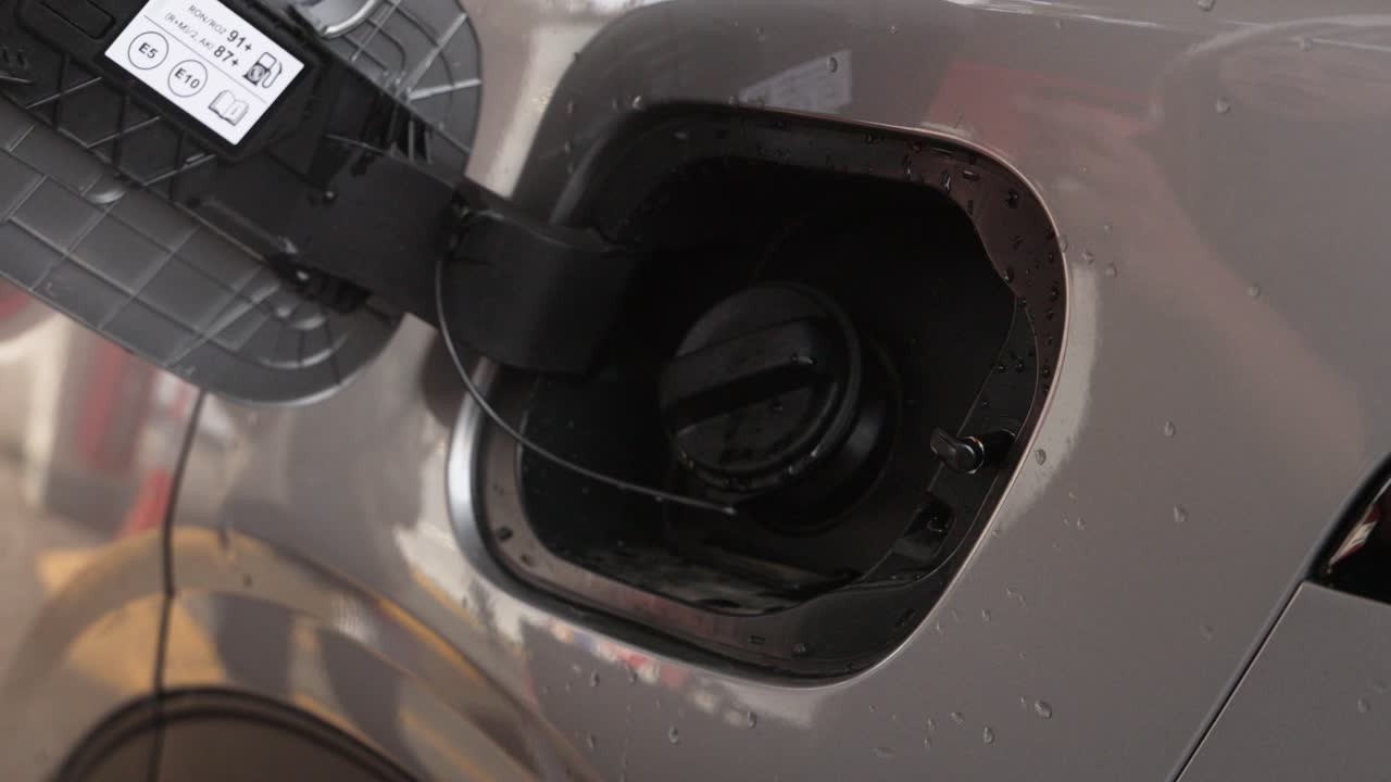 abriendo a mano la tapa del tanque de combustible de un coche