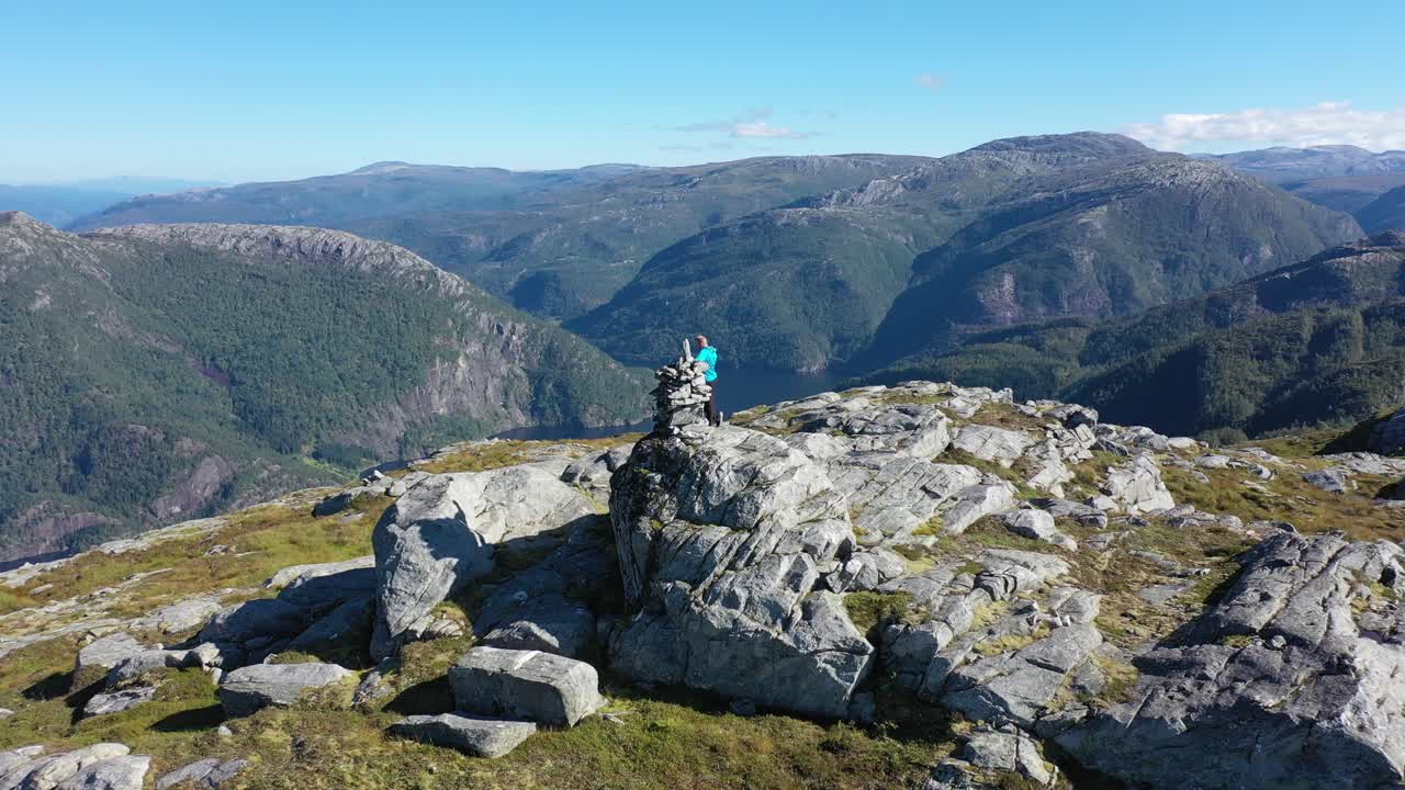 antena orbitando lentamente alrededor de un hombre parado en la cima de la montaña stamneshella en noruega con bolstadfjorden en el fondo y rodeado de un espectacular paisaje montañoso