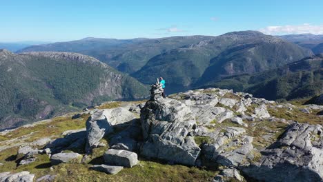 antena orbitando lentamente alrededor de un hombre parado en la cima de la montaña stamneshella en noruega con bolstadfjorden en el fondo y rodeado de un espectacular paisaje montañoso
