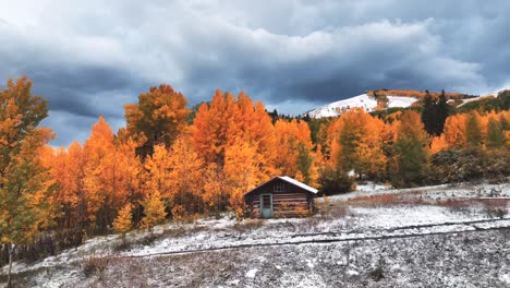 A-remote-cabin-with-a-dusting-of-snow-surrounded-by-peaking-fall-colors-in-Colorado