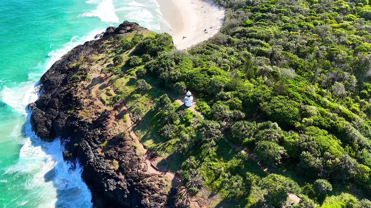 울창한 해안 지점에 있는 등대, 바다의 파도가 부히고