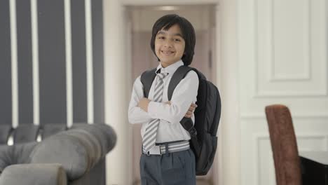 retrato de un niño de escuela indio feliz de pie con las manos cruzadas