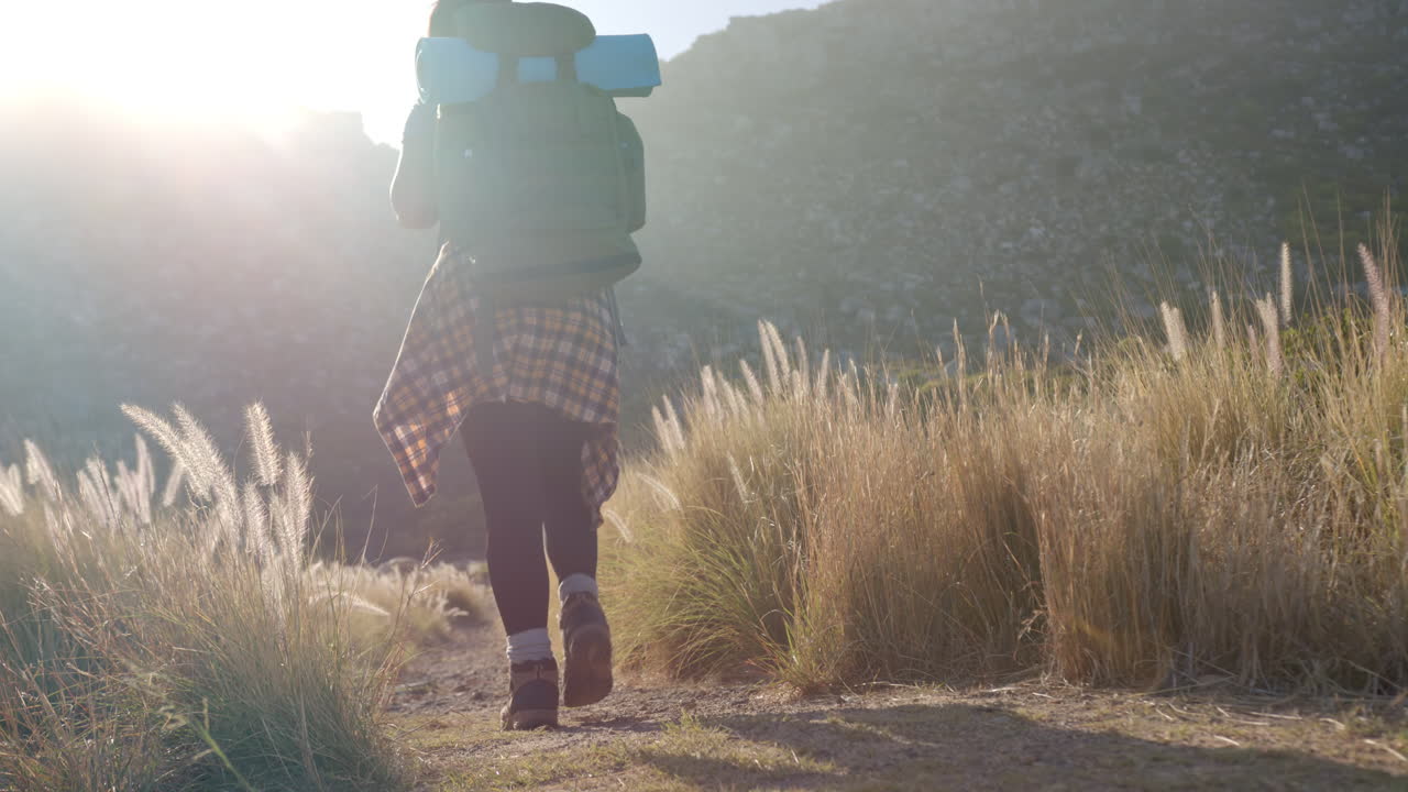 Hiking in mountains, woman with backpack and yoga mat walking on trail, copy space