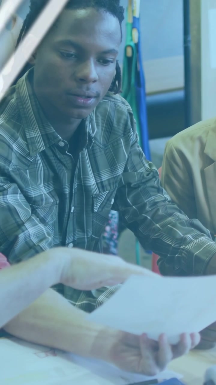 Vertical video: Plaid team lead taking paper from peer, reading for business while overlay growing